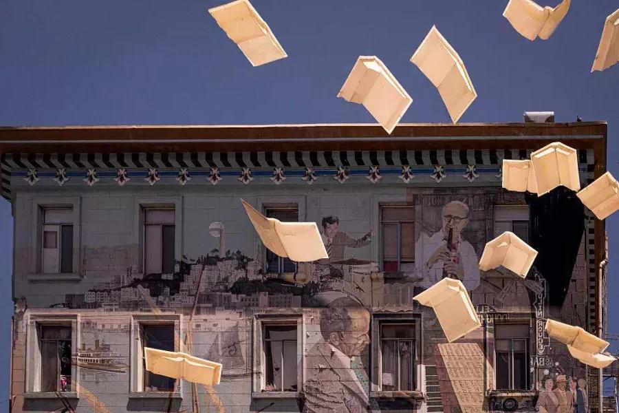 Außenaufnahme des City Lights Bookstore in San Francisco mit einem Wandgemälde aus Büchern und schwebendem Papier.