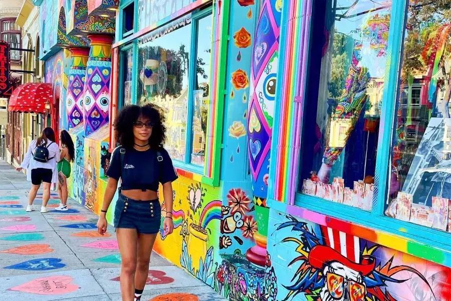 Une femme marche dans une rue bordée de bâtiments colorés dans le quartier de Haight-Ashbury à San Francisco.